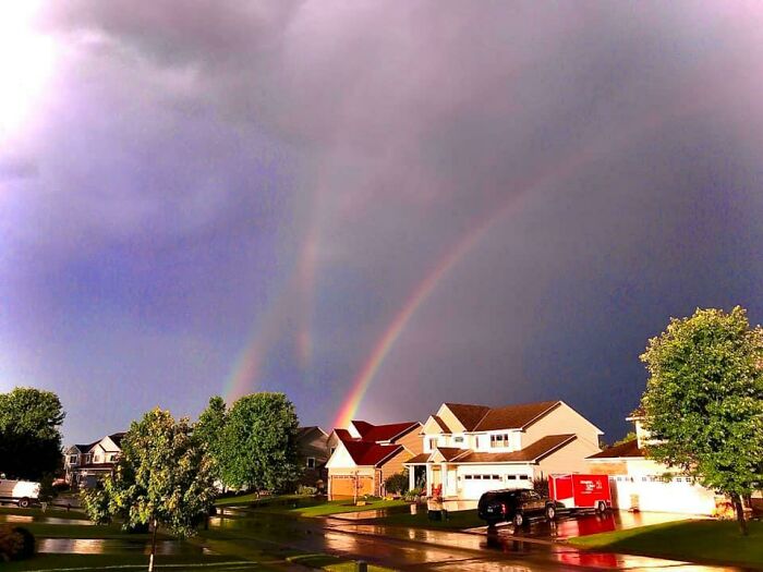 Double rainbow over a suburban neighborhood at sunset, illustrating real-life glitches in the matrix phenomenon.