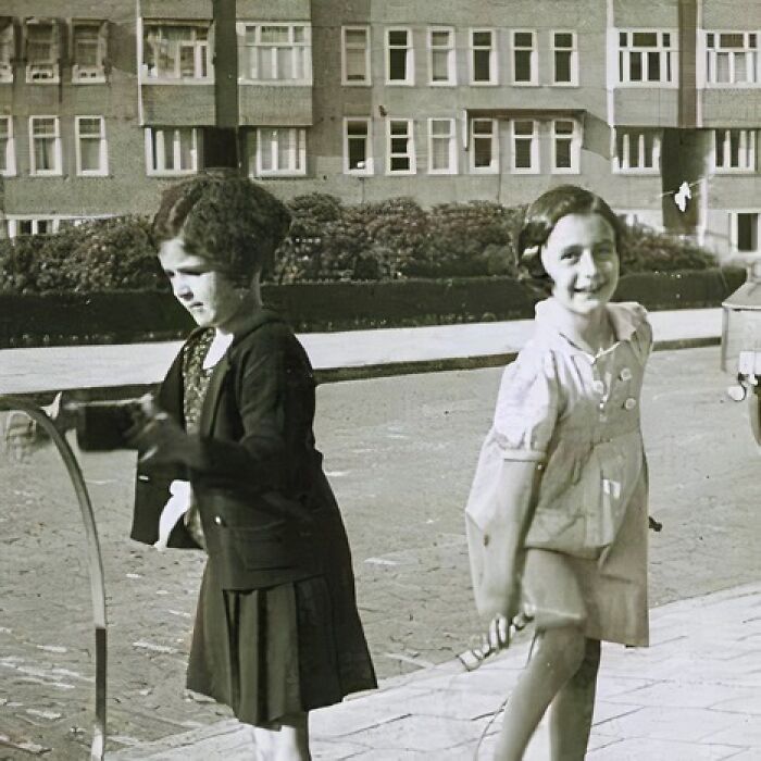 Two girls playing with a hoop and stick outdoors, captured in one of the most unique old photos with incredible stories.