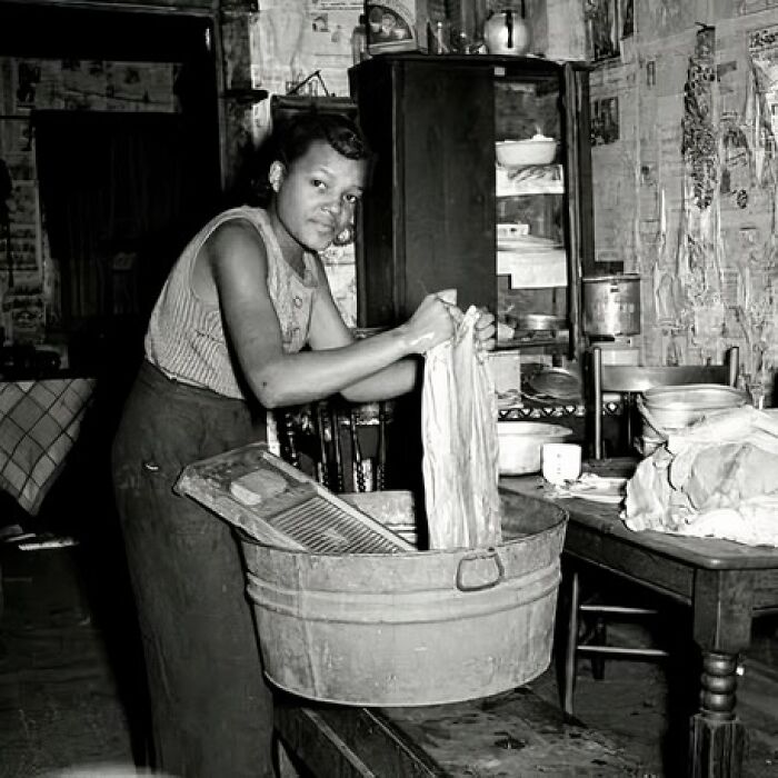 Black and white photo of a woman hand-washing clothes in a tub, one of the most unique old photos with stories behind them.