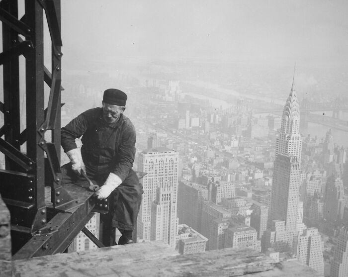 Construction worker high above New York City skyline in a rare and interesting historical photograph.