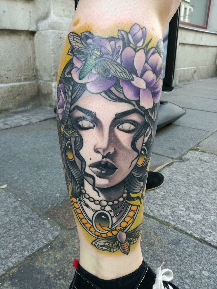 Tattoo on leg of a woman with white eyes, purple flowers, and moths, evoking creepy real things witnessed or heard about.