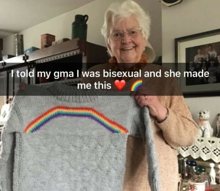 Elderly woman smiling and holding a handmade sweater with a rainbow, showcasing wholesome people and animals.
