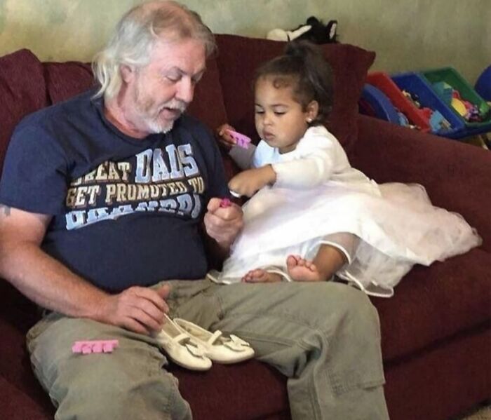 Older man and young girl sharing a wholesome moment on a couch, showing kindness and warmth between people.