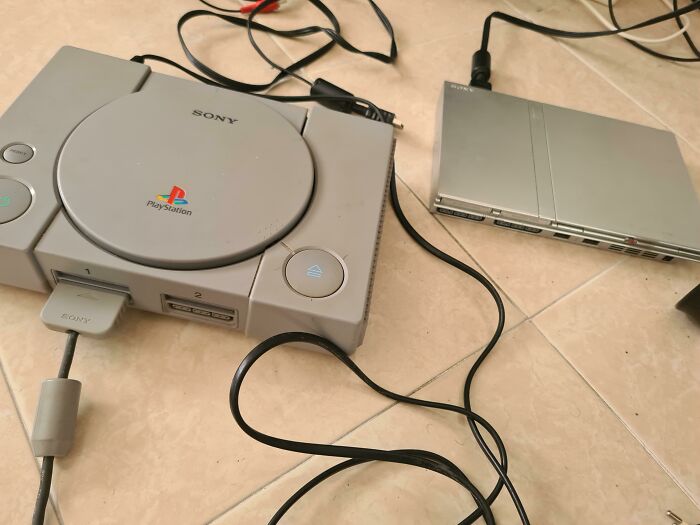 Vintage Sony PlayStation console and accessories on a tiled floor, showcasing retro gaming equipment and unbelievable luck setup.