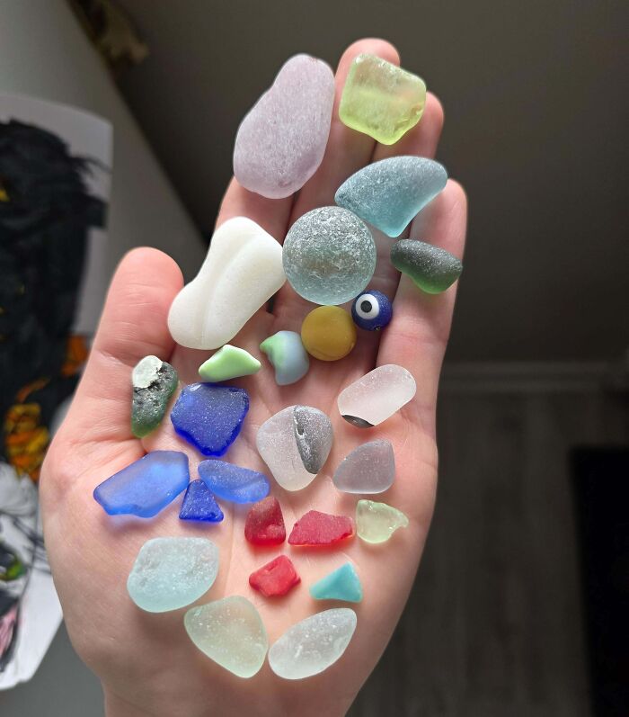 Hand holding colorful sea glass and stones, showcasing amazing luck with rare collectible pieces found on the beach.