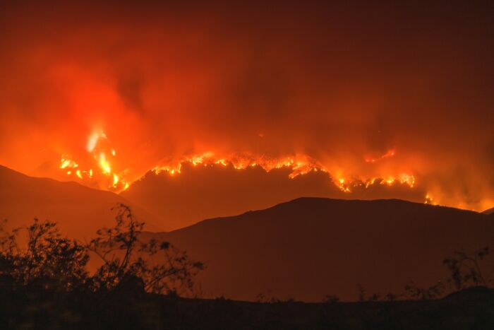 Mountain wildfire blazing intensely at night, illustrating one of the most catastrophic wildfires in recent history.