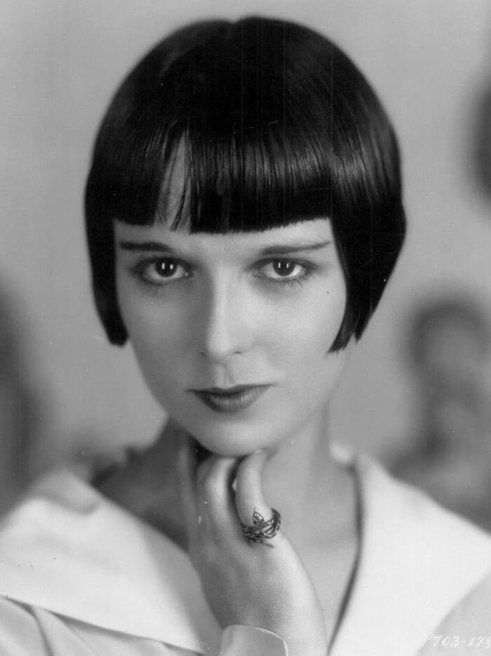 Black and white century-old photo of a woman with a bob haircut, embodying timeless beauty and classic elegance.