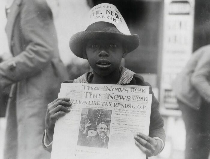 Young boy selling newspapers on the street in a rare and interesting historical photograph from the early 1900s.