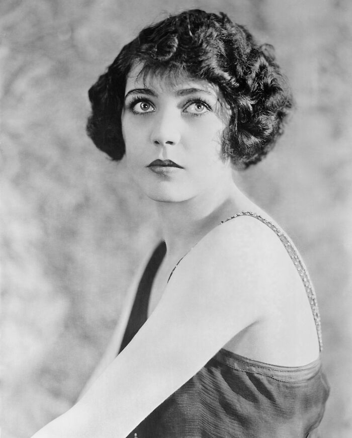 Black and white portrait of a woman representing timeless beauty from century-old photos with vintage hairstyle and attire.