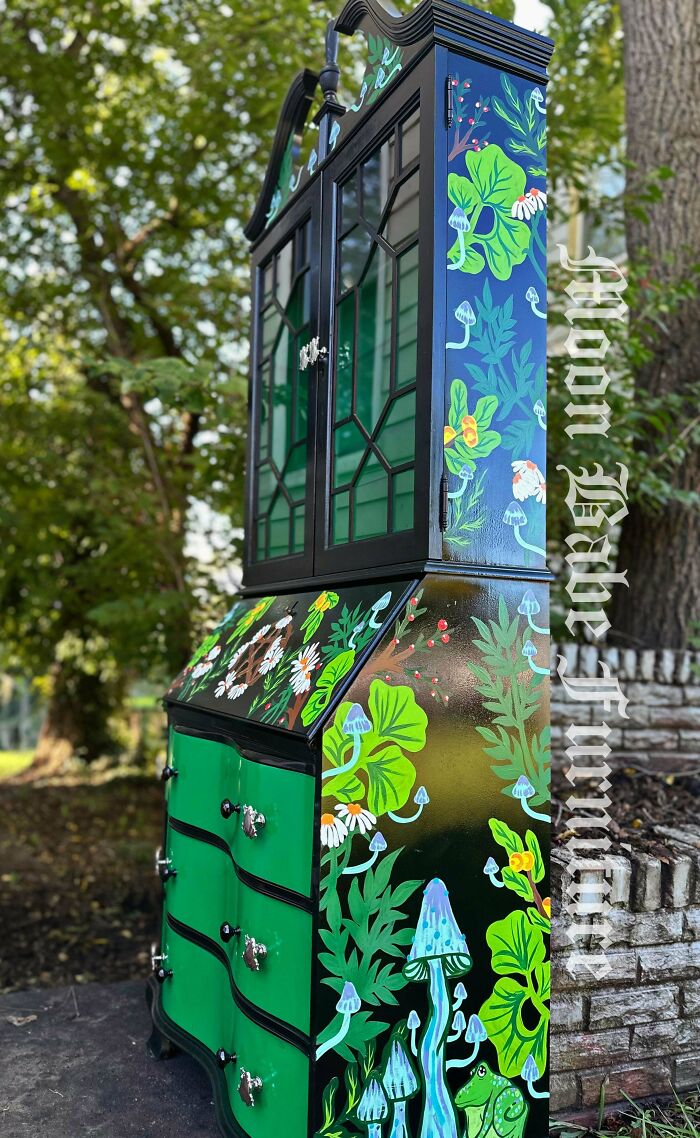 Hand-painted furniture flipping with vibrant floral and mushroom designs on a refurbished cabinet outdoors.