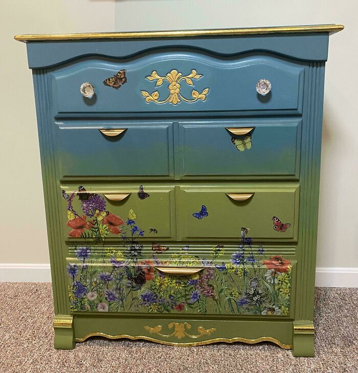 Colorfully painted furniture flipping project featuring butterflies and flowers with gold accents on a vintage chest of drawers.