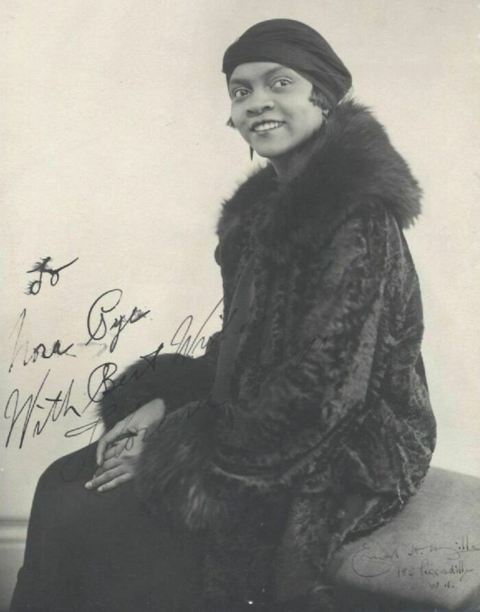 Vintage portrait of a woman in fur coat and headscarf, representing timeless beauty in century-old photos.
