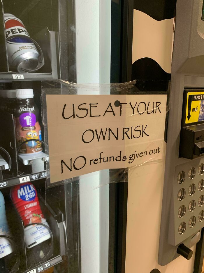 Vending machine in a school with a sign warning use at your own risk and no refunds, illustrating school conditions.