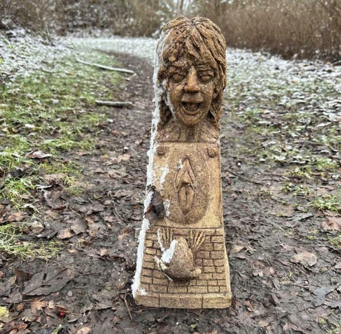 Creepy and terrifying carved wooden figure found in the forest surrounded by snow and fallen leaves.