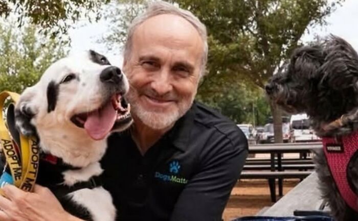Man smiling with two dogs while sharing a story of hope and wholesome people and animals making a difference.