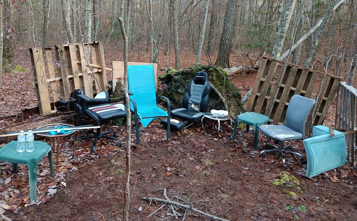 Abandoned chairs and pallets arranged in a circle deep in the forest, creating a creepy and terrifying scene.