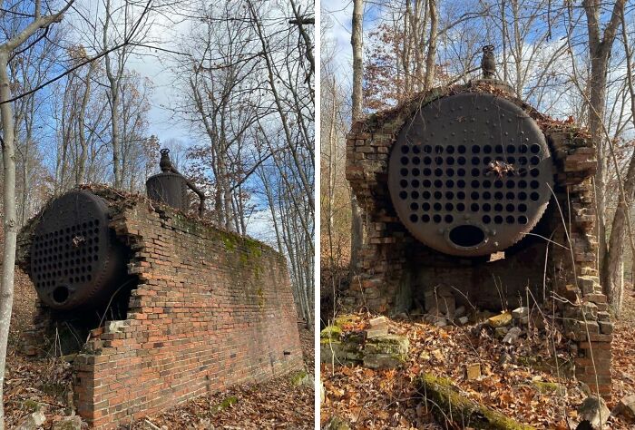 Rusty abandoned industrial boiler partially collapsed in forest, surrounded by bare trees and fallen leaves, evoking creepy discoveries.