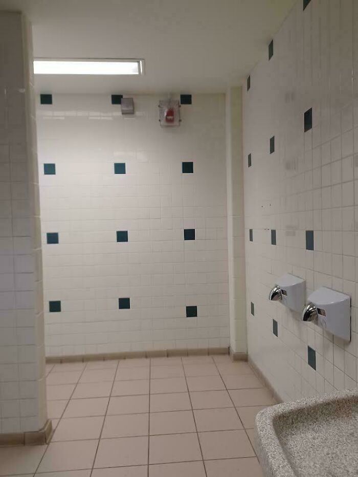 School restroom with tile walls and hand dryers demonstrating schools are not created equal or great.