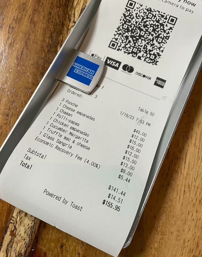 Restaurant receipt showing an economic recovery fee listed among other charges and payment options on a table check.