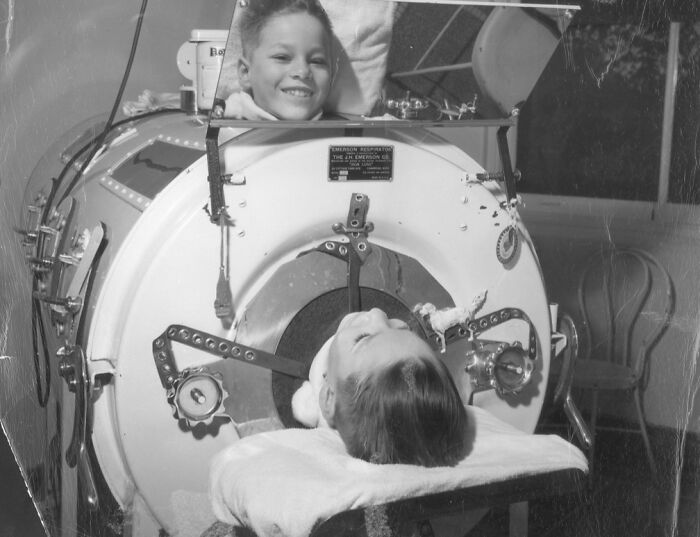 Child undergoing treatment in an unsettling medical device from the past, highlighting historical medical equipment.
