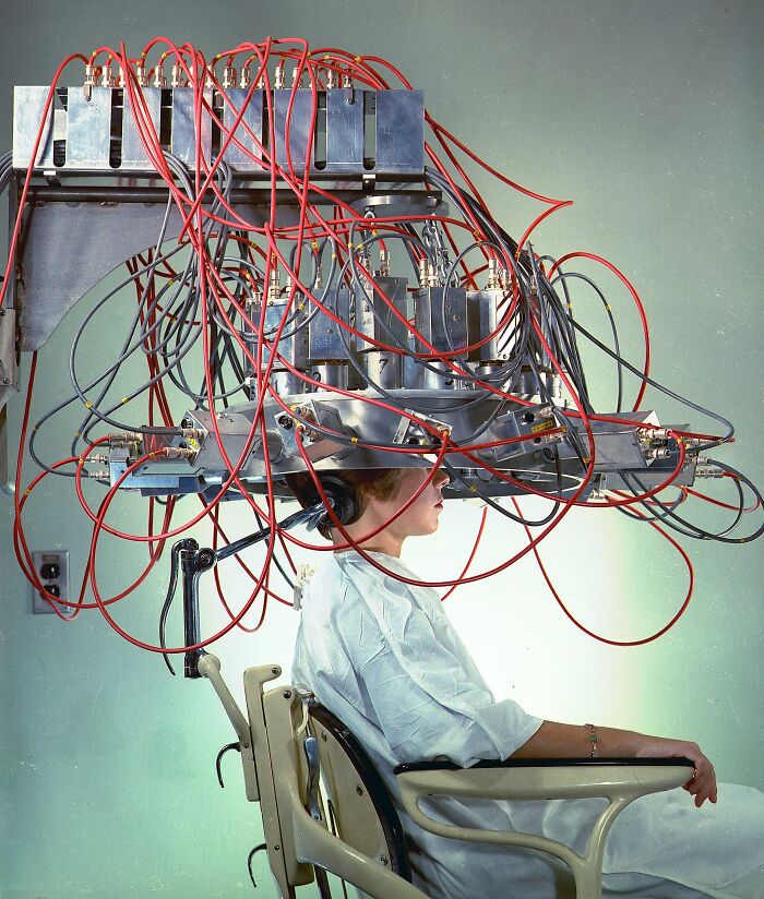 Patient undergoing brain scan with an unsettling medical device featuring numerous wires and metal components from the past