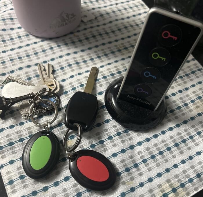 Key finder device with colorful key icons next to a set of keys on a checkered cloth surface.