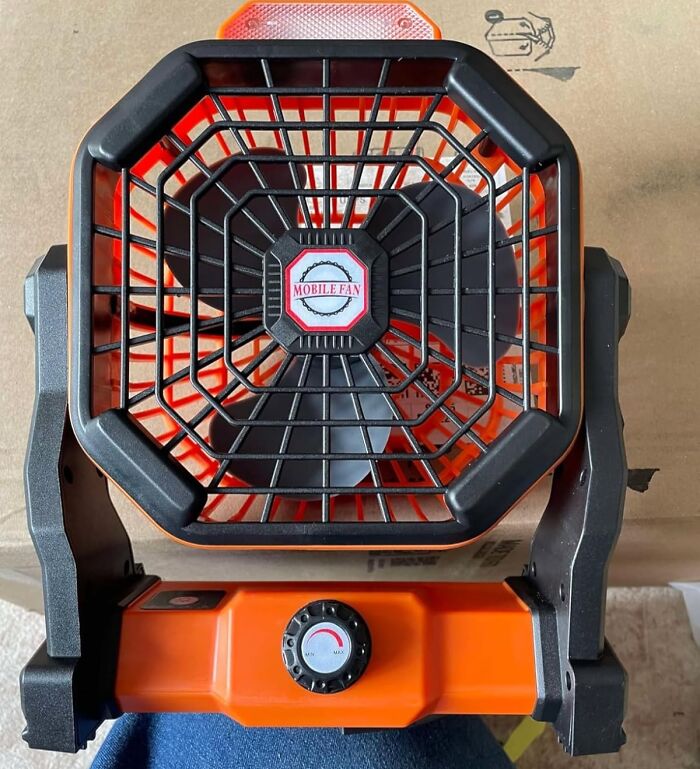 Portable orange and black mobile fan with adjustable dial, perfect for camping hacks and enhancing comfort in the great outdoors.