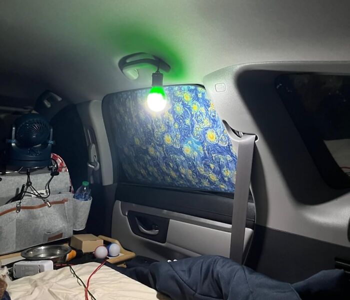 Car interior camping setup with hanging LED light and window cover, showcasing useful camping hacks for the great outdoors.