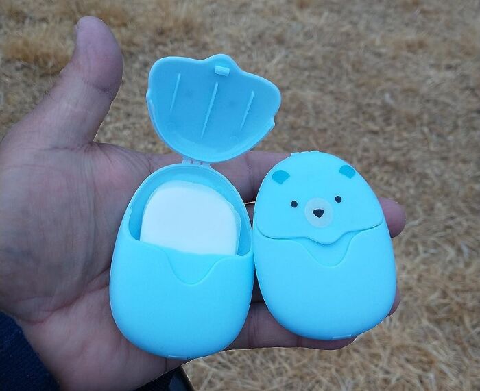 Hand holding blue bear-shaped portable soap case, showcasing camping hacks for the great outdoors.