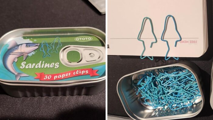 Tin of sardine-shaped paper clips on a dark surface, with some clipped to a notebook, enhancing workspace holiday décor.