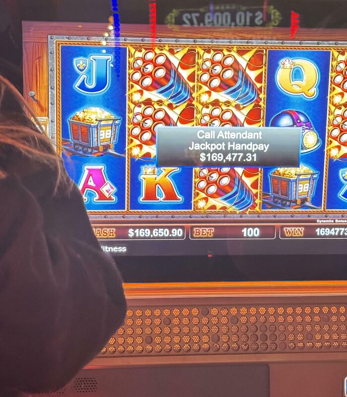 Person’s back facing a slot machine showing a jackpot handpay win of $169,477, capturing unbelievable luck moment.