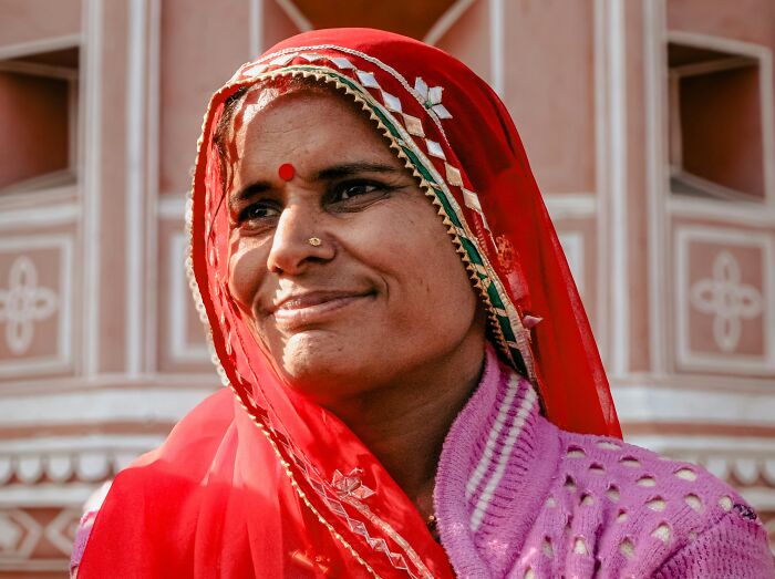 Smiling woman in traditional red headscarf and pink sweater, representing themes of Jesus wrote the Bible myths.