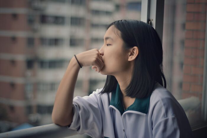 Young woman looking thoughtfully out a window, reflecting on common religious myths about Jesus and the Bible.