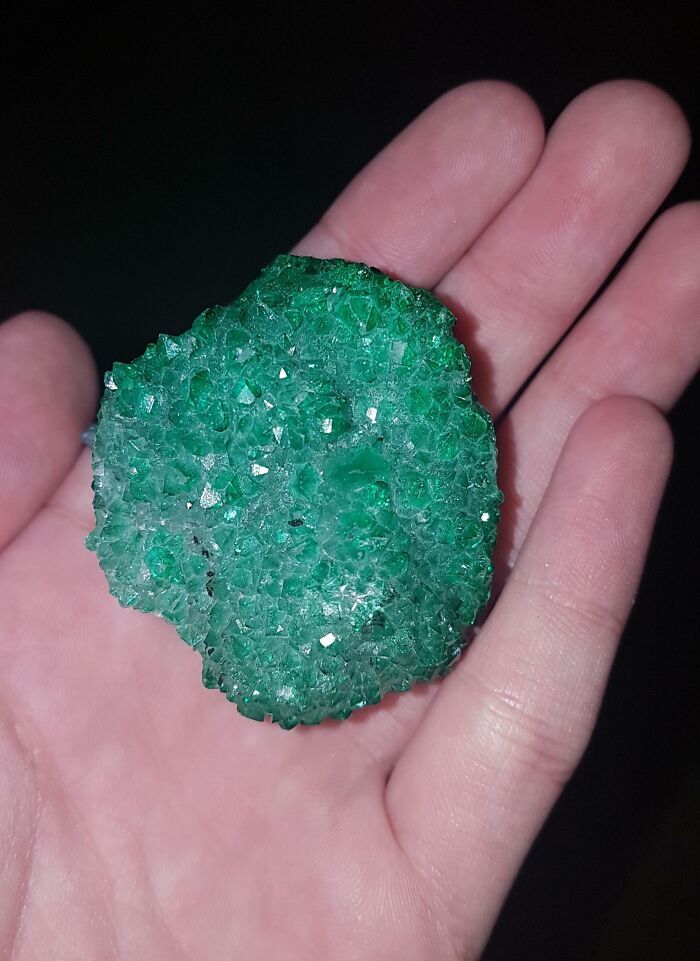 Hand holding a sparkling green crystal, one of the amazing photos showing people experiencing unbelievable luck.