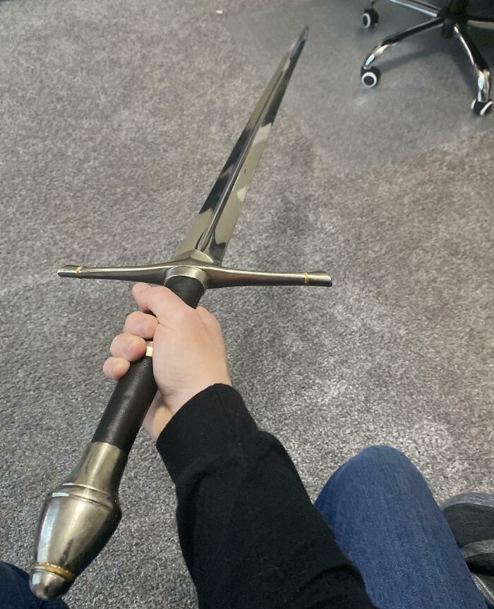 Person holding a medieval sword indoors on a carpeted floor, showcasing unbelievable luck with a rare find.