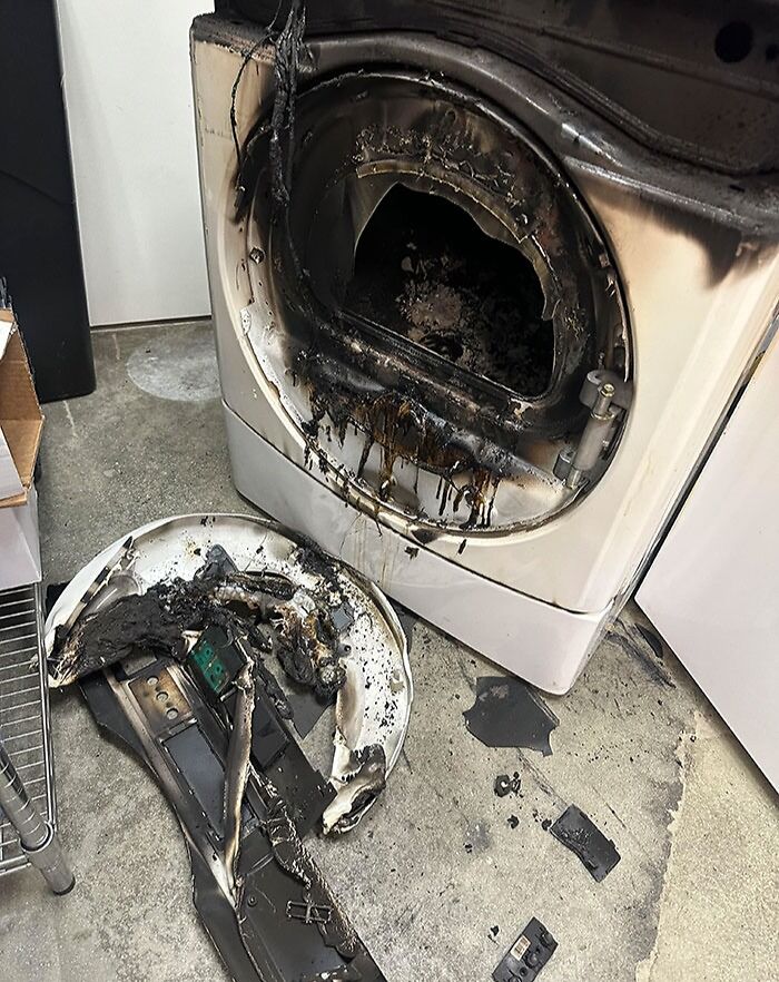 Burnt and melted front-load washer parts on the floor showing unbelievable luck in avoiding injury from fire damage.