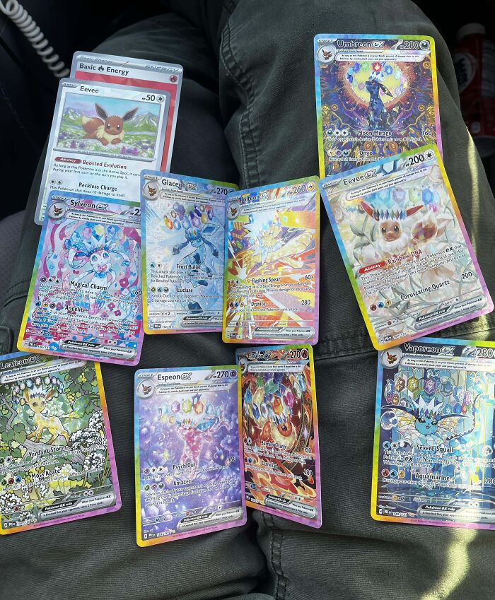 Collection of rare Pokémon cards displayed on someone's lap, showcasing amazing luck in acquiring valuable cards.