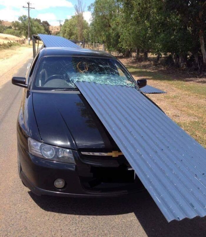 Black car with a large metal sheet through the windshield, showing unbelievable luck in avoiding serious injury.