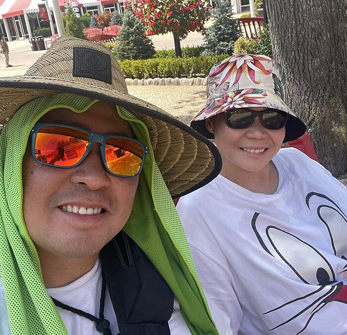 Two people wearing wide-brimmed hats and sunglasses outdoors using heatwave hacks for sun protection during summer heat.