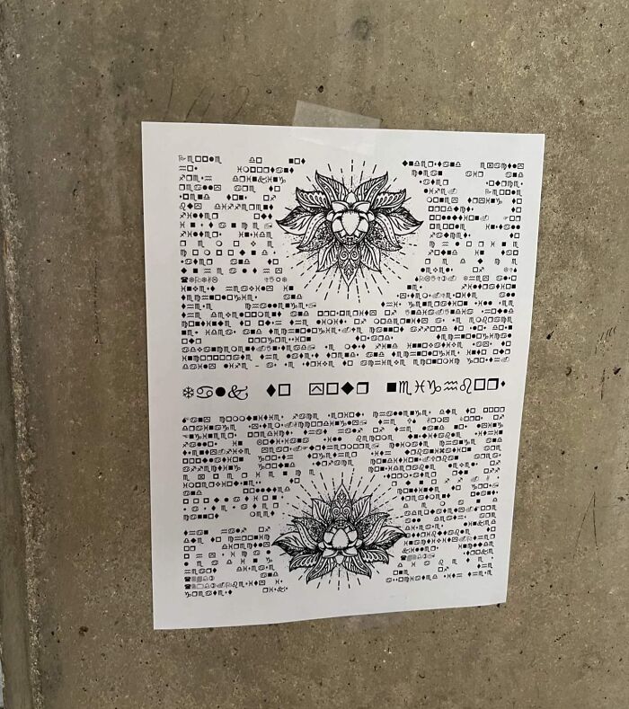 Sheet of paper with cryptic symbols and floral designs taped to a concrete wall, illustrating interesting mysteries that still baffle people.