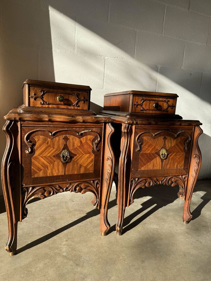 Pair of beautiful old wooden vintage nightstands with ornate carvings and decorative hardware in natural light.