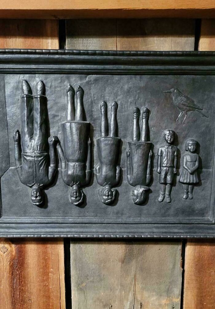 Black vintage wall plaque featuring raised figures of a family and a bird, showcasing interesting and beautiful old things.