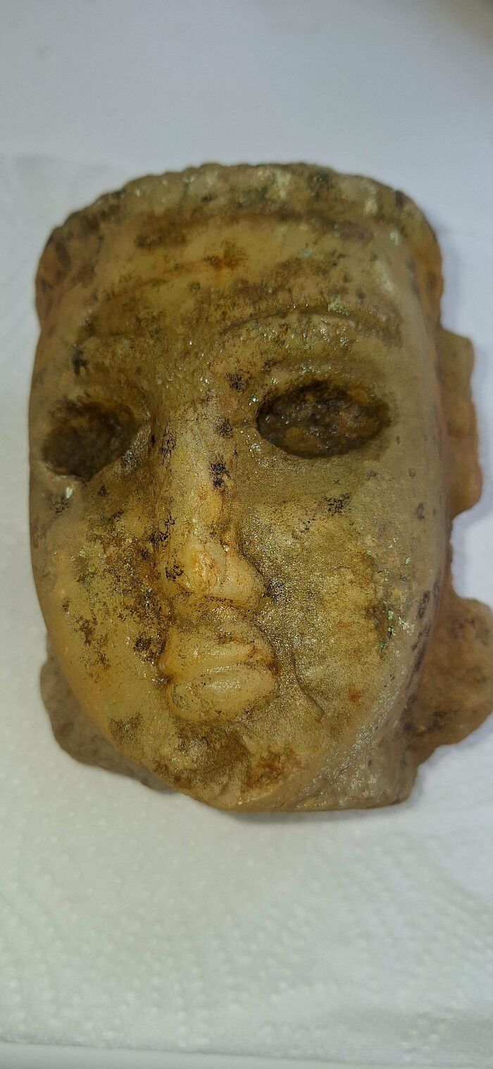 Close-up of a weathered old carved stone face, showcasing an interesting and beautiful antique artifact.