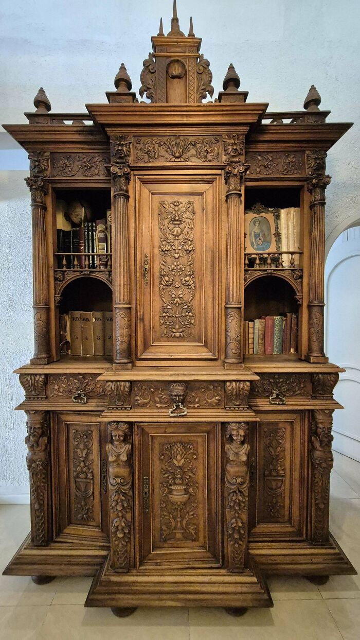 Ornately carved old wooden cabinet with books and decorative details, showcasing beautiful antique craftsmanship.