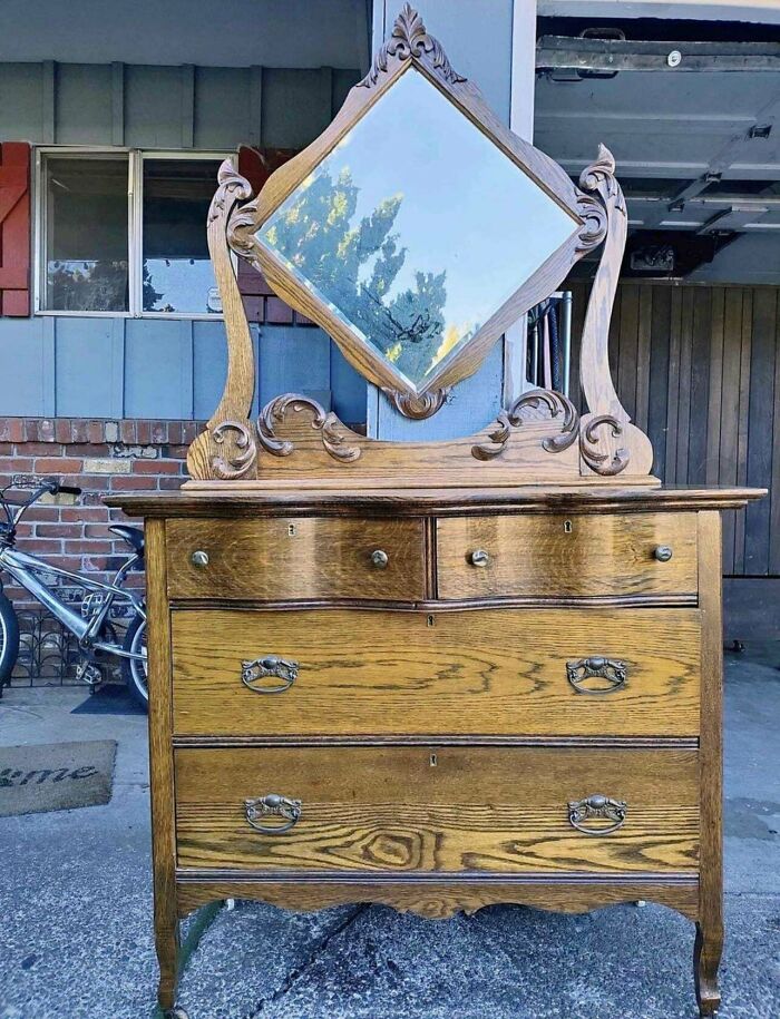 Antique wooden dresser with ornate mirror and multiple drawers, showcasing a beautiful old vintage design and craftsmanship.