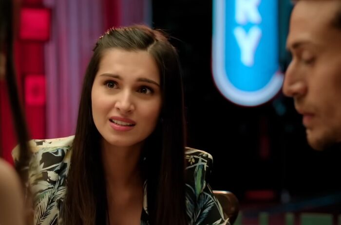 Young woman speaking to a man in a dimly lit scene from one of the worst movie sequels in cinematic crimes.