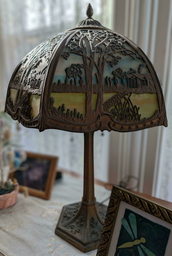 Antique decorative lamp with detailed scenic metalwork shade, showcasing beautiful old things with artistic craftsmanship.