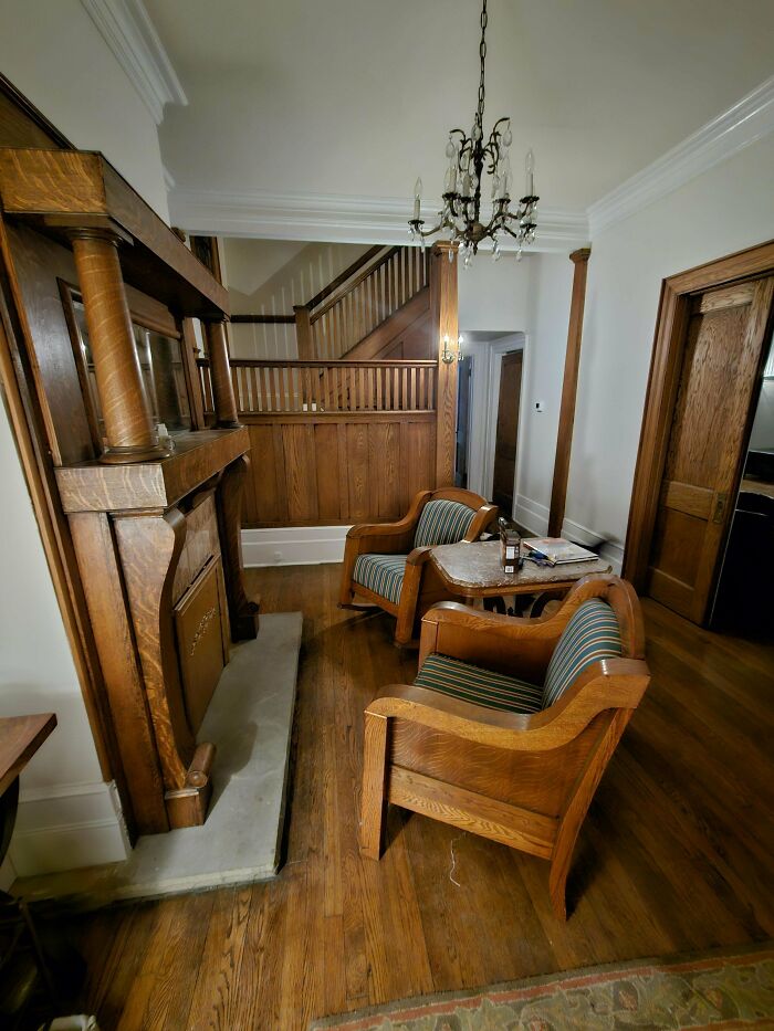Vintage wooden chairs and fireplace in a cozy living room showcasing beautiful old things people enjoy owning.