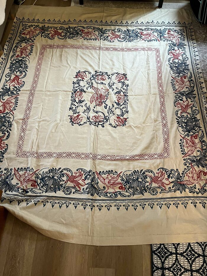 Vintage embroidered textile with intricate red and blue floral patterns, showcasing beautiful old things people enjoy owning.