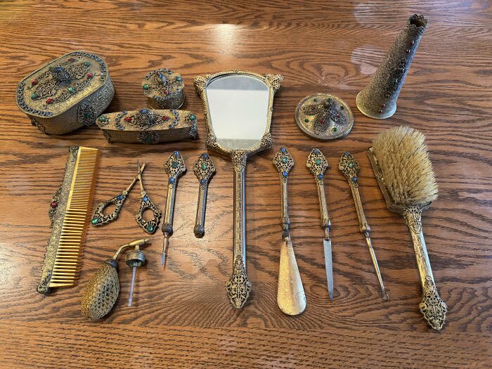 Collection of interesting and beautiful old vintage vanity items with intricate designs and colorful gemstone accents on wood surface